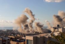 Ex-Sailor Linked To ISIS Drone Plot Smoke rising from buildings in a city with a coastal view