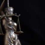 Lady Justice statue holding balanced scales against a dark background