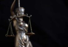 Crime Of Violence Loophole Strikes Again Lady Justice statue holding balanced scales against a dark background