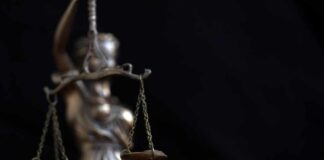 Lady Justice statue holding balanced scales against a dark background