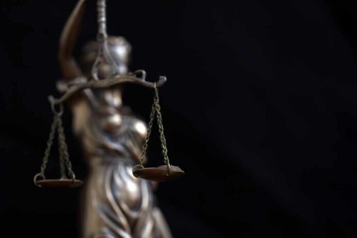 Lady,Justice,Large,Statue,In,Law,On,Black,Backdrop.,Law Lady Justice statue holding balanced scales against a dark background