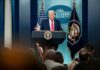 A man speaking at a podium during a press conference at the White House