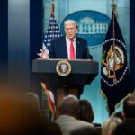 A man speaking at a podium during a press conference at the White House