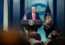 A man speaking at a podium during a press conference at the White House