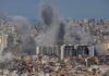 Nine Dead, General Down — Truce In Tatters Smoke rising from buildings in a densely populated urban area