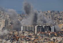 Nine Dead, General Down — Truce In Tatters Smoke rising from buildings in a densely populated urban area