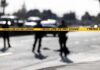 Questions Grow After Fatal ICE Shooting Police tape cordons off a street with blurred officers and vehicles in the background