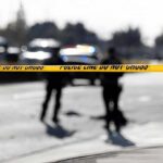 Questions Grow After Fatal ICE Shooting Police tape cordons off a street with blurred officers and vehicles in the background