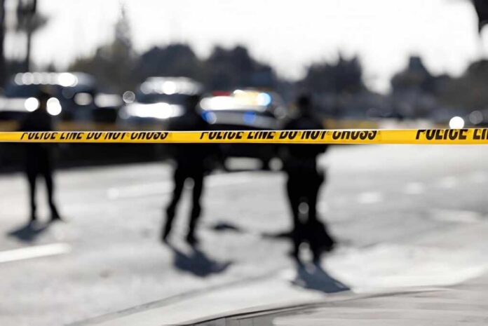 2758684351 Police tape cordons off a street with blurred officers and vehicles in the background