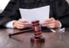 Ex-NFL Scout Convicted Of Double Murder A judge holding documents with a gavel in the foreground