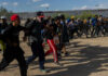 Defund Regret Rocks Democrats A group of migrants walking in a desert area towards a border