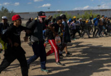 Defund Regret Rocks Democrats A group of migrants walking in a desert area towards a border