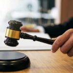 DOJ Backs Down In Press Battle Judge's hand holding a gavel over a sound block