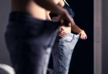 America’s New Weight-Loss Breakthrough Person trying on oversized pants in front of a mirror