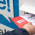 DOJ Warns States: Comply Or Face Charges Person placing a mail-in ballot into a voting drop box