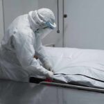 Diary Reveals Alleged Rapists After Euthanasia Healthcare worker in PPE zipping a body bag on a gurney