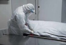 Diary Reveals Alleged Rapists After Euthanasia Healthcare worker in PPE zipping a body bag on a gurney