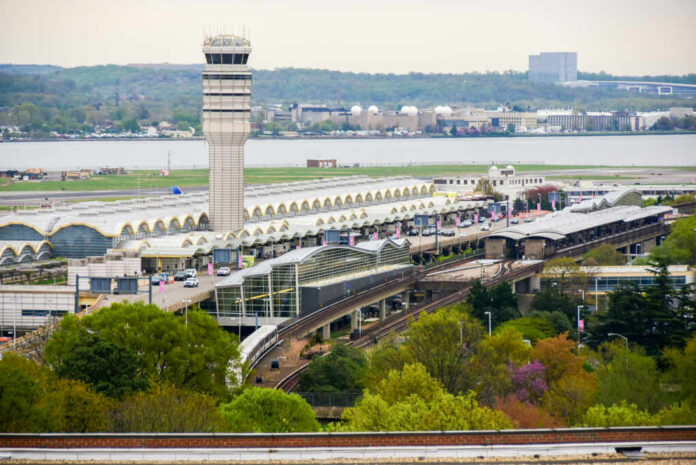 View of an airport terminal with a control tower and surrounding greenery