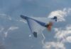 Navy Plans Drone Carrier Future A drone flying high above the clouds with a visible propeller
