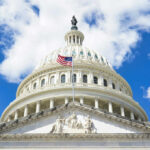 Constitution Clash Ignites After Trump Setback The U.S. Capitol building with an American flag flying in front against a blue sky