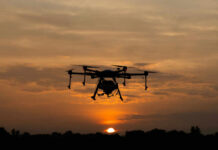 A drone flying against a sunset sky, silhouetted by the evening light