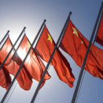Pacific Missile Launch Raises Concerns Multiple Chinese flags waving against a clear blue sky with sunlight in the background
