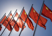 Pacific Missile Launch Raises Concerns Multiple Chinese flags waving against a clear blue sky with sunlight in the background