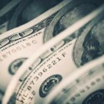 Rich Donors Quietly Rewrite Childhood Close-up of folded hundred dollar bills