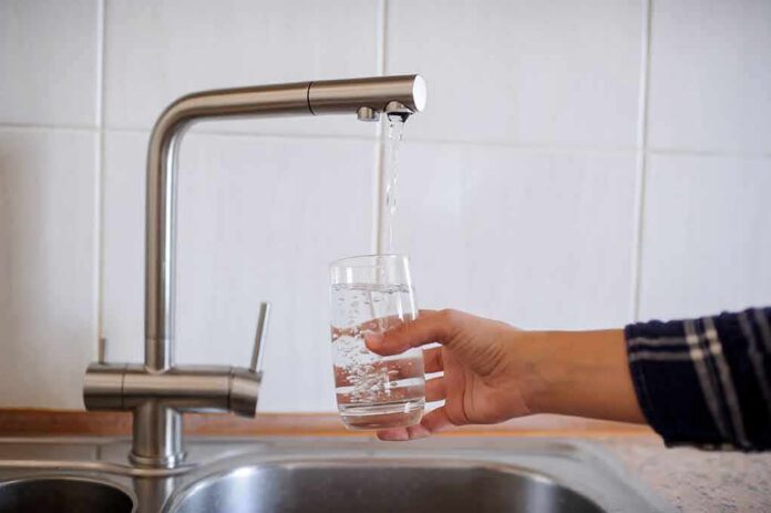 shutterstock_1128611180-1 Hand filling a glass with water from a kitchen faucet