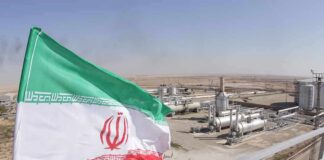 Iran flag over an oil and gas facility in a desert landscape