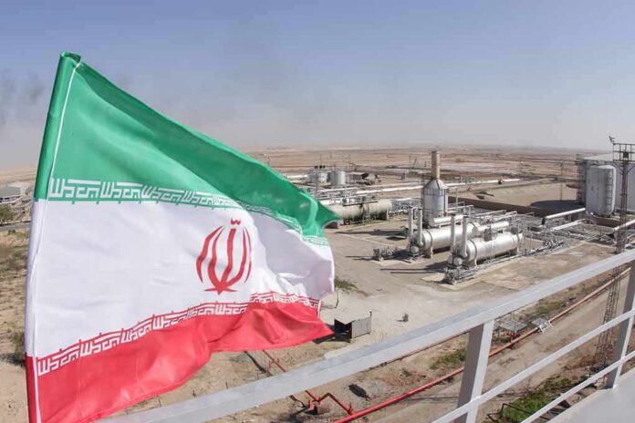 shutterstock_1227310843 Iran flag over an oil and gas facility in a desert landscape