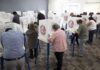 Voters fill out ballots at polling booths in a busy voting room