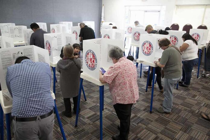 shutterstock_133686017 Voters fill out ballots at polling booths in a busy voting room
