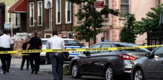 Police at urban street crime scene with yellow tape around parked cars