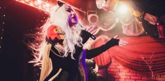 Drag performer singing on stage with dramatic lighting