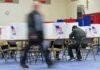 Power Move Silences 300,000 Voters Voter fills out ballot at polling station with privacy booths