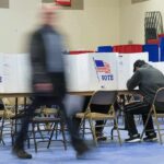 Power Move Silences 300,000 Voters Voter fills out ballot at polling station with privacy booths