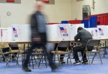 Voter fills out ballot at polling station with privacy booths