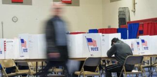 Voter fills out ballot at polling station with privacy booths