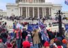 Crowd with flags gathered outside a large white government building