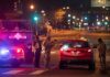 Security officers stop a red taxi at a night checkpoint