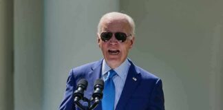 man in blue suit speaking at a podium with presidential seal