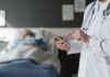 Doctor using tablet beside hospital patient