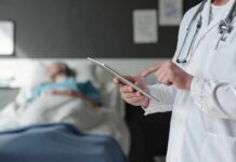 Doctor using tablet beside hospital patient
