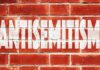 A New Fight Erupts Over Democrats Brick wall with large white stencil text