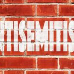 A New Fight Erupts Over Democrats Brick wall with large white stencil text