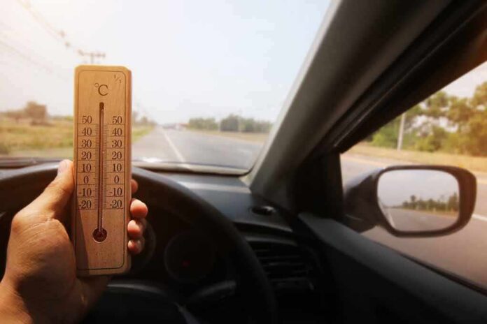 shutterstock_741907621 Hand holding a wooden thermometer inside a car on a sunny road