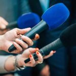 The Pentagon Remembers 184 Lives Reporters holding colorful microphones