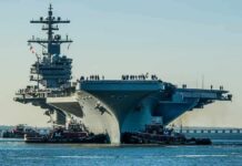 War Bills Blow Hole In Navy Budget Aircraft carrier guided by tugboats in a harbor