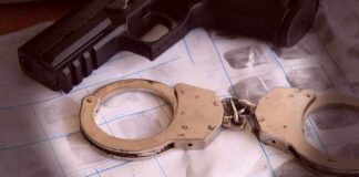 Handcuffs on fingerprint sheets beside a handgun